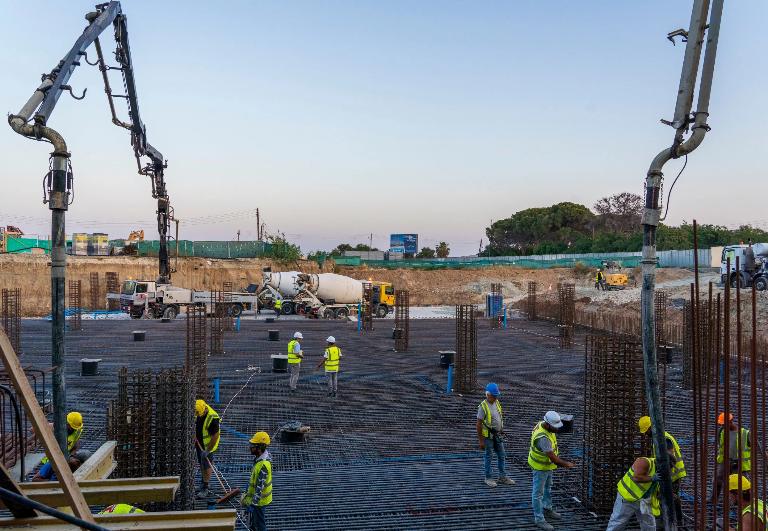 Crew placing rebar ahead of a concrete pour, with pump trucks and mixers on site